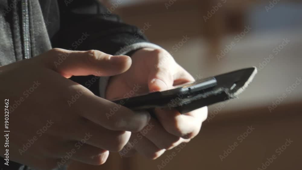 The man walks around the room with phone in hand and typing a message The man walks around the room with phone in hand and typing a message