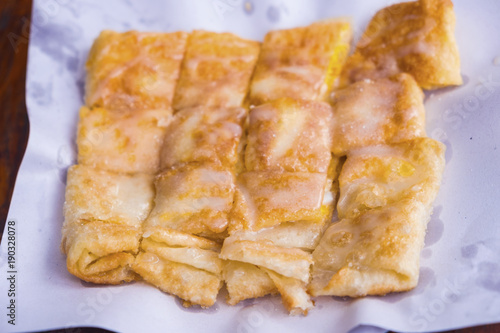 Roti with egg and sprinkle with white sugar and sweetened condensed milk, cut into square pieces, placed on white paper.