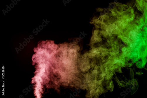 Thick colorful smoke of green, red, yellow on a black isolated background. Background from the smoke of vape