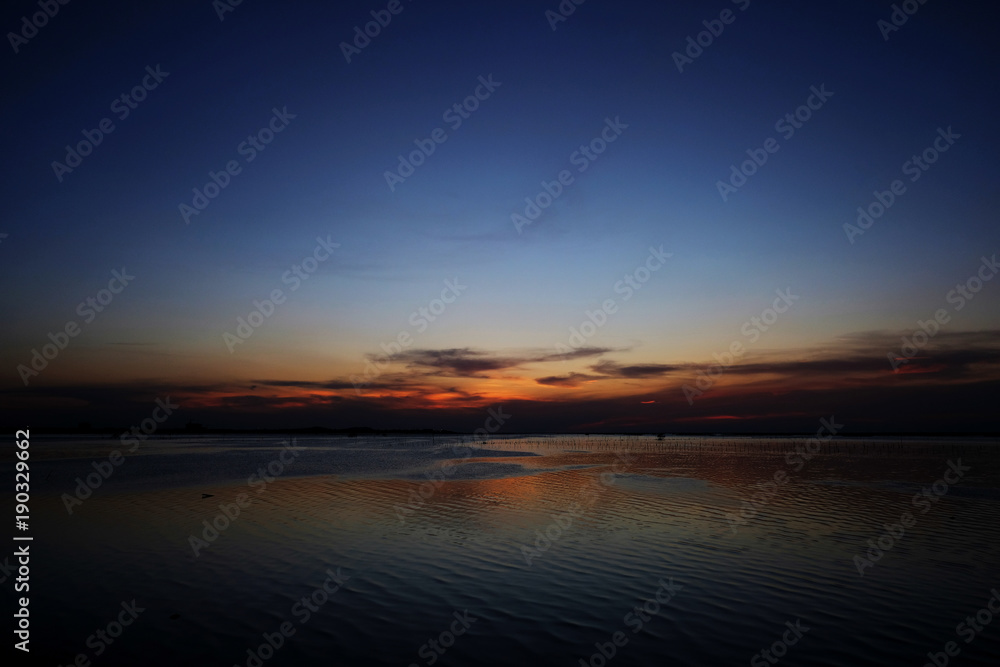 Beautiful sunset on the sea with blue sky and orange light reflection in water
