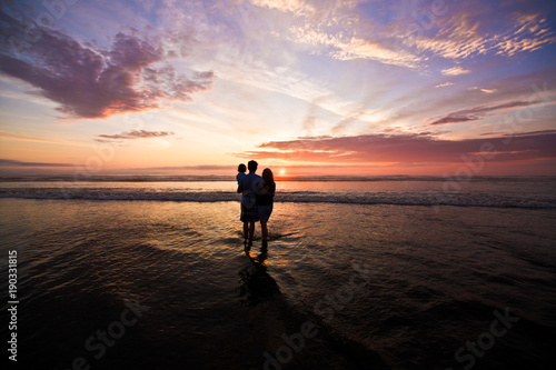 Silhouette of father and mother holding daughter on the beach at the sunset time. Outdoor and friendly family concept.Pacific Ocean, Sea Side Oregon USA, Family Vacation Time