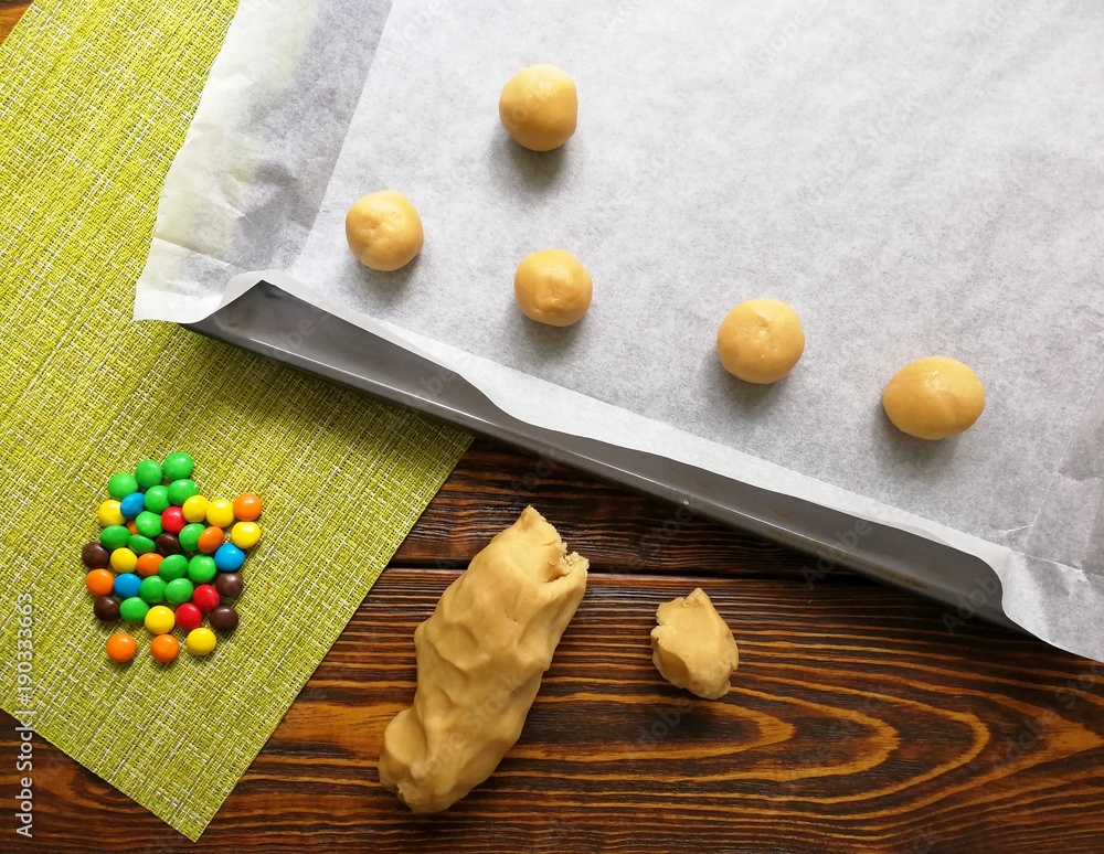 baking cookies with colorful candy m&m in the kitchen , on a wooden table baking cookies with colorful candy m&m in the kitchen , on a wooden table
