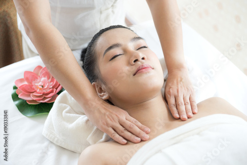 beautiful and healthy young woman relaxing with face and shoulder massage at beauty spa salon