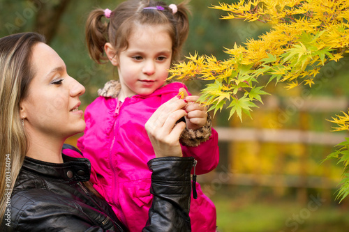 Beautiful Young Mother Showing Leaves to Four Years Old Cute Toddler Girl in Japanese Park in Portland Oregon USA, Portrait Close-up, Happy Family Concept, Colorful Fall Colors