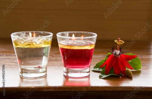 Red Granadilla Flower and Water Candle /Two water candle in a glass and Red Granadilla Flower on a brown wooden floor, additional romance for a lover's date.