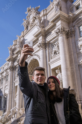 Young couple, taking a photo with the Trevi fountain in the background