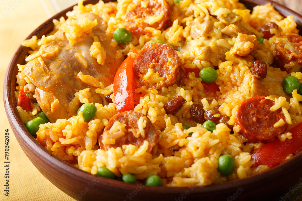 Delicious Arroz Valenciana with rice, meat, sausage chorizo, vegetables and spices close up in a bowl. horizontal Delicious Arroz Valenciana with rice, meat, sausage chorizo, vegetables and spices close up in a bowl. horizontal