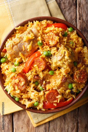 Paella Valenciana with meat, sausage chorizo, vegetables and spices close-up in a bowl. vertical top view