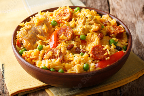 Delicious food: Arroz Valenciana with rice, meat, sausage, raisins and vegetables close-up in a bowl. horizontal
