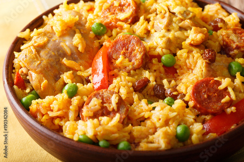 Delicious Arroz Valenciana with rice, meat, sausage chorizo, vegetables and spices close up in a bowl. horizontal