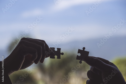 Closeup image of two hands holding a jigsaw puzzle with feeling love