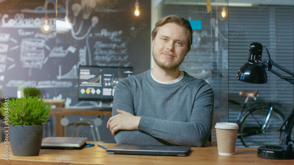 Handsome Young Office Employee Finishes His Work Closes Laptop Computer and Charmingly Smiles on Camera. He's Working in the Creative Stylish Office. Handsome Young Office Employee Finishes His Work Closes Laptop Computer and Charmingly Smiles on Camera. He's Working in the Creative Stylish Office.