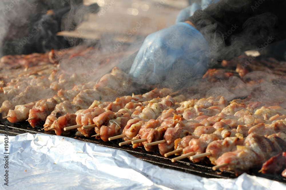 Kebab on wooden skewers on grill. Shashlik or shashlyk – meat skewers on grill outside. Shish kebab on a barbecue. Roast meat on BBQ. Selective focus through smoke. Kebab on wooden skewers on grill. Shashlik or shashlyk – meat skewers on grill outside. Shish kebab on a barbecue. Roast meat on BBQ. Selective focus through smoke.