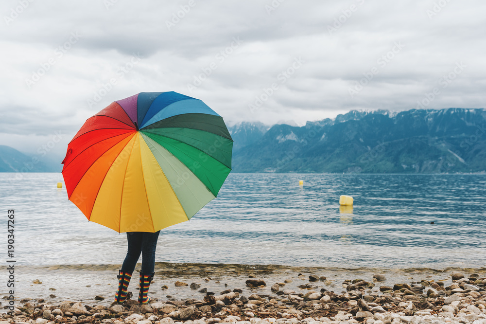Child enjoying amazing view on Lake Geneva, Switzerland. Kid with huge colorful umbrella admiring mountains