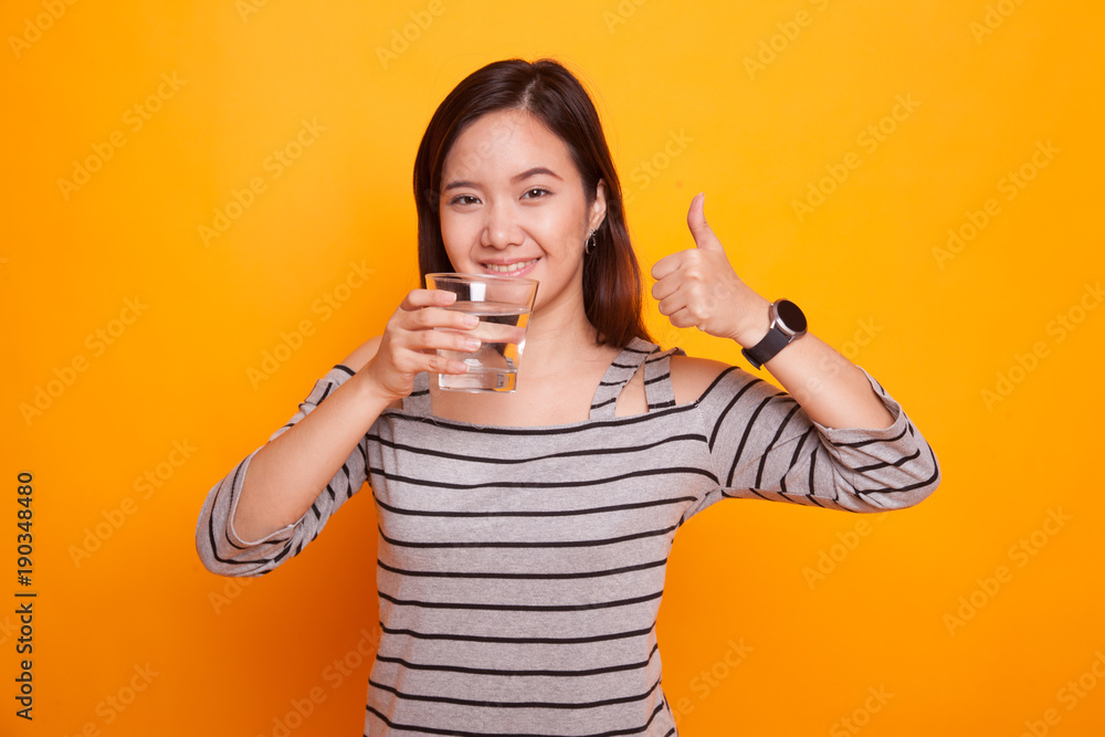 Young Asian woman thumbs up with a glass of drinking water. Young Asian woman thumbs up with a glass of drinking water.