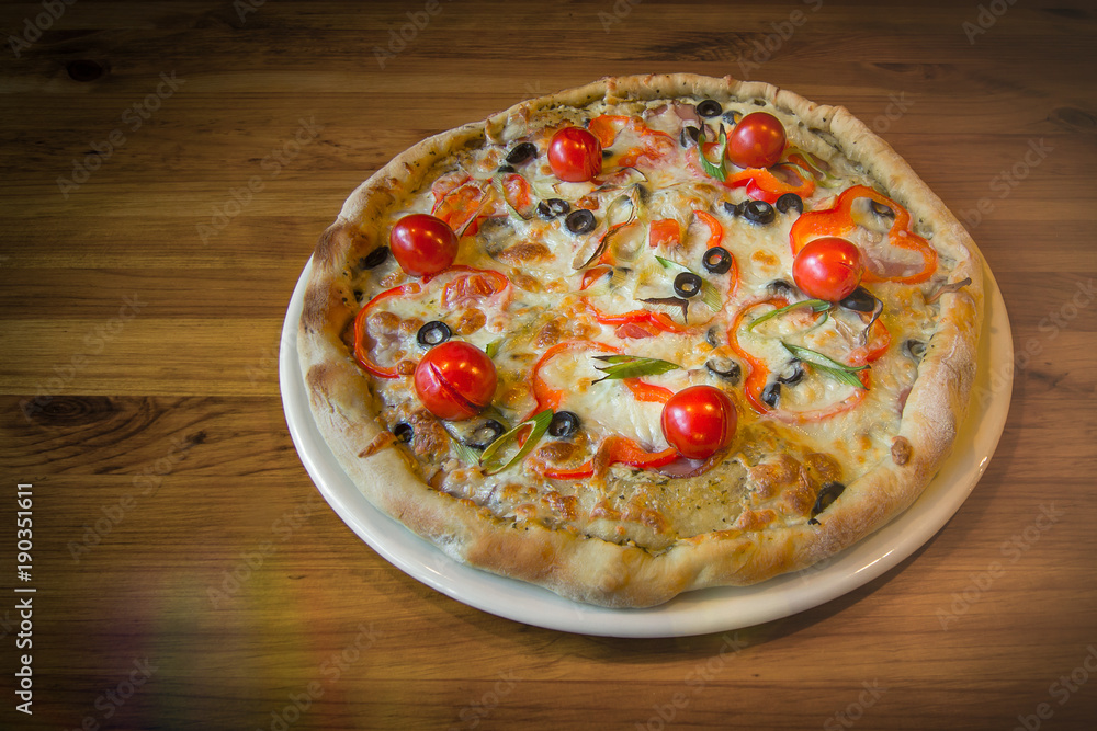 Delicious fresh hot pizza in a pizzeria on a wooden background Delicious fresh hot pizza in a pizzeria on a wooden background