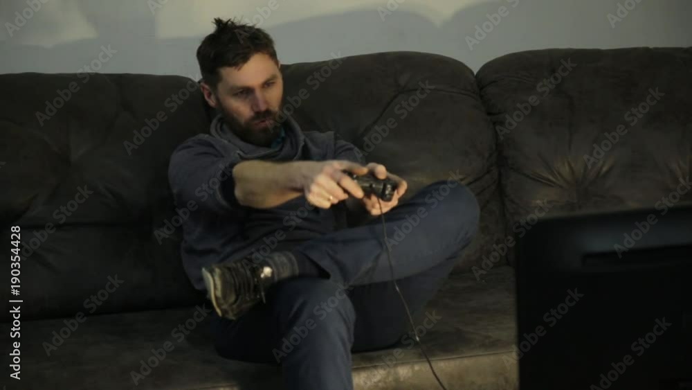 Attractive young man plays on a modern video console in dark Attractive young man plays on a modern video console in dark
