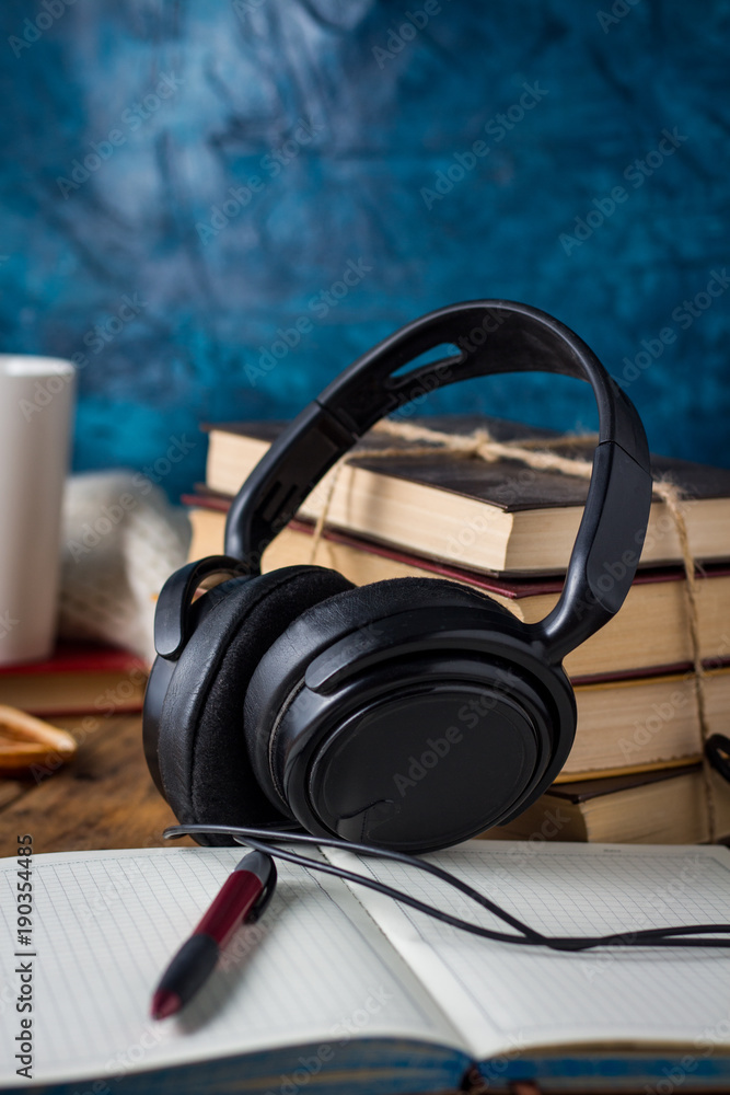 Books are stacked, Headphones, White Cup, open Diary on a wooden background. The Concept of Audio Books Books are stacked, Headphones, White Cup, open Diary on a wooden background. The Concept of Audio Books