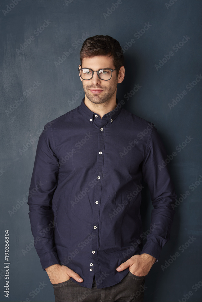 Young businessman portrait. Portrait shot of a relaxed young man sitting at dark background while looking at camera and smiling. Young businessman portrait. Portrait shot of a relaxed young man sitting at dark background while looking at camera and smiling.