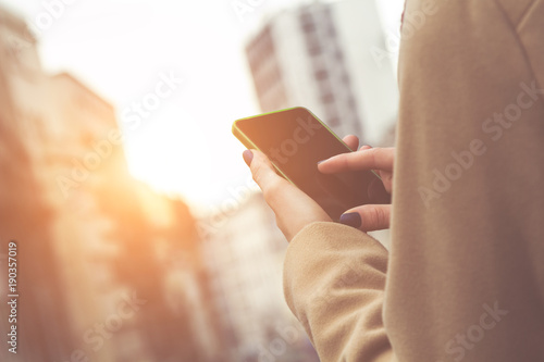 Photos Girl using cellphone while walking on the cuty street.