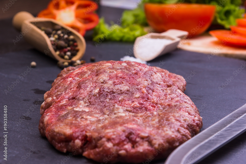 Fresh raw beef burgers to cook a hamburger on a dark background Fresh raw beef burgers to cook a hamburger on a dark background