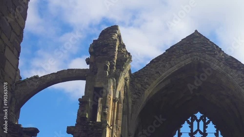 The arch windows of the ruins of Melrose Abbey in Scotland and clouds