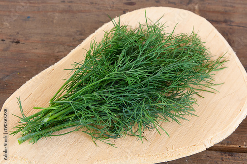 Bunch of fresh organic dill on a rustic wooden background. photo