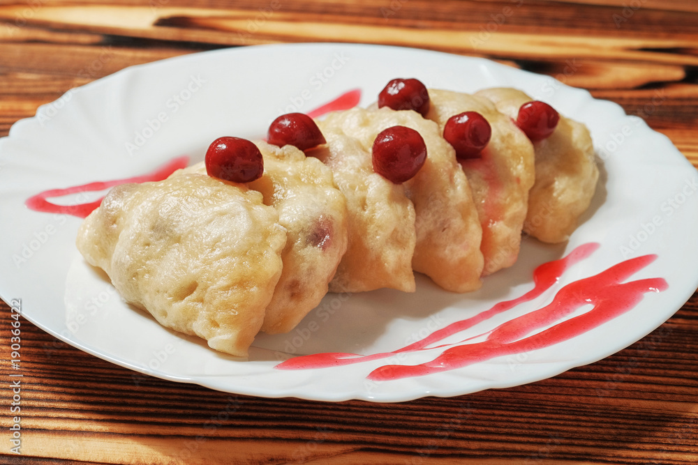 White plate with sweet boiled dough vareniki with cherry. Ukrainian national dish. White plate with sweet boiled dough vareniki with cherry. Ukrainian national dish.