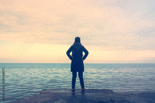 proud woman at the sea, lonely lady looking the horizon in winter season photo
