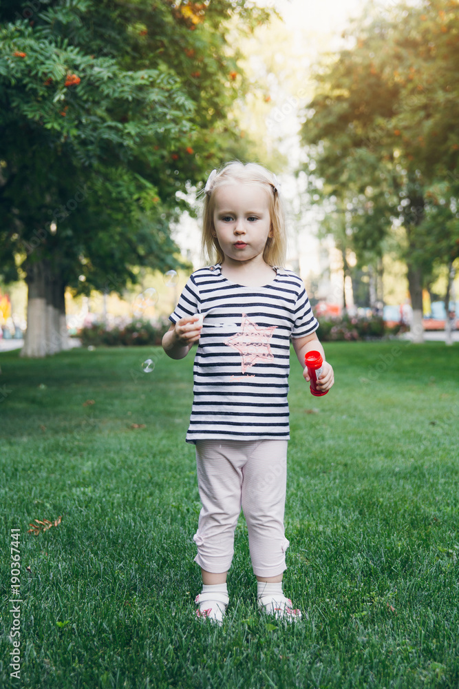 Little girl inflate soap bubbles on the lawn Little girl inflate soap bubbles on the lawn
