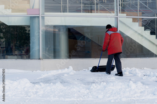 A worker clears snow after a snowstorm in front of a large office building