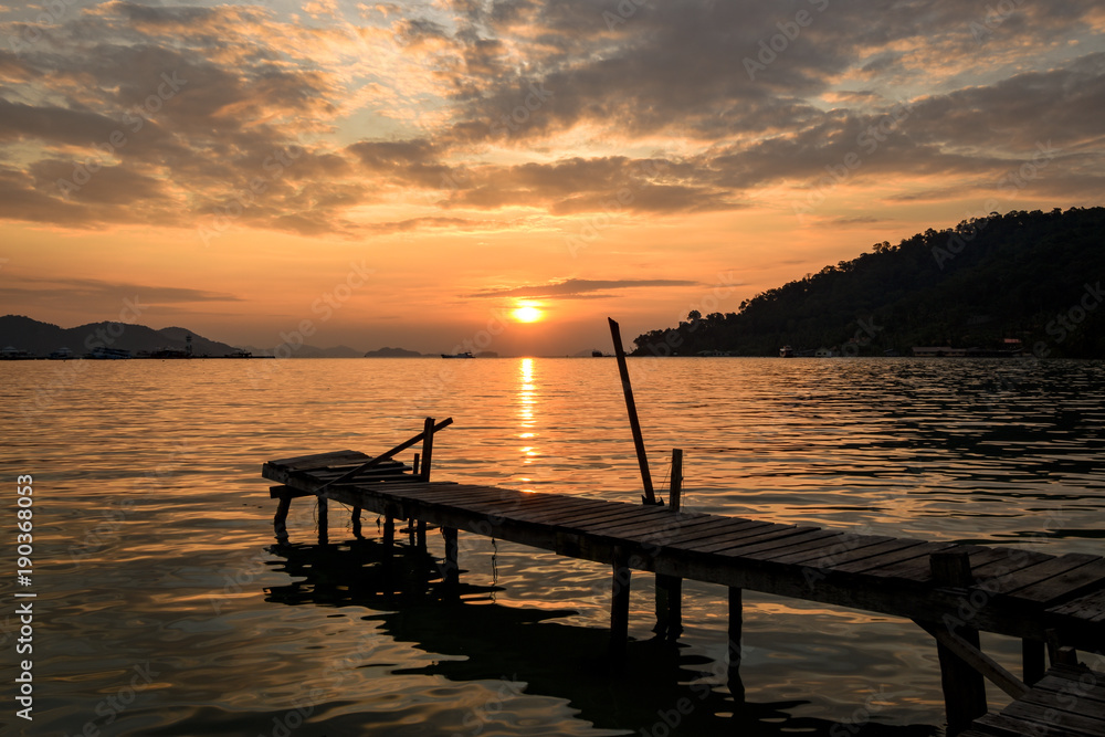 tropical sunrise with wooden jetty over island