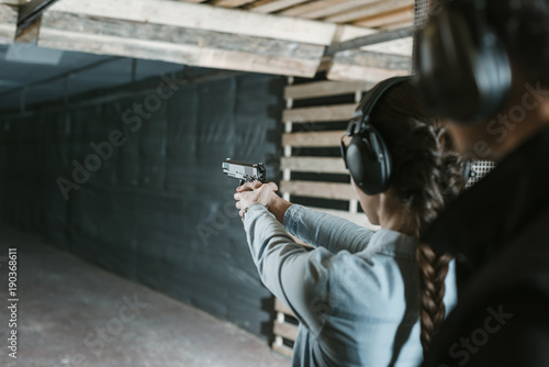 rear view of girl shooting with gun in shooting gallery photo