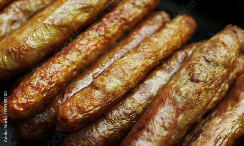 Barbecued meat sausages (bratwurst) close up. Grilled delicious sausages macro shoot.