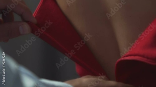 Gallant male slowly unzipping red dress on female back, helping to undress