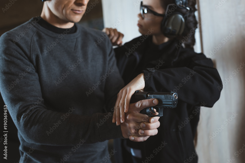 cropped image of instructor describing client how to hold gun cropped image of instructor describing client how to hold gun