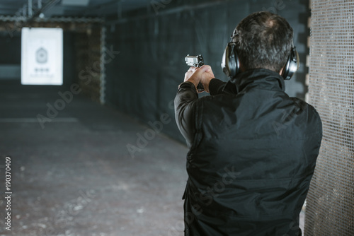 Quadro em tela rear view of man aiming gun at target in shooting range