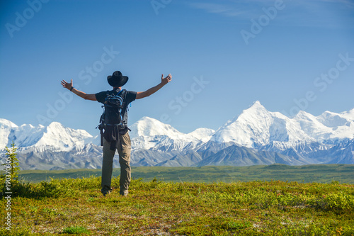 man with outstreched arms in front of Alaskan Range, Denali photo