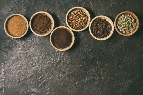 Variety of grounded  instant coffee  different coffee beans  brown sugar in wooden bowls in row over dark texture background. Top view  space. Toned image