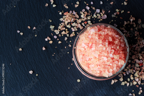 Pink Himalayan salt in jar on dark slate background. Top view.