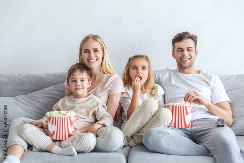 excited young family watching movie on couch at home excited young family watching movie on couch at home