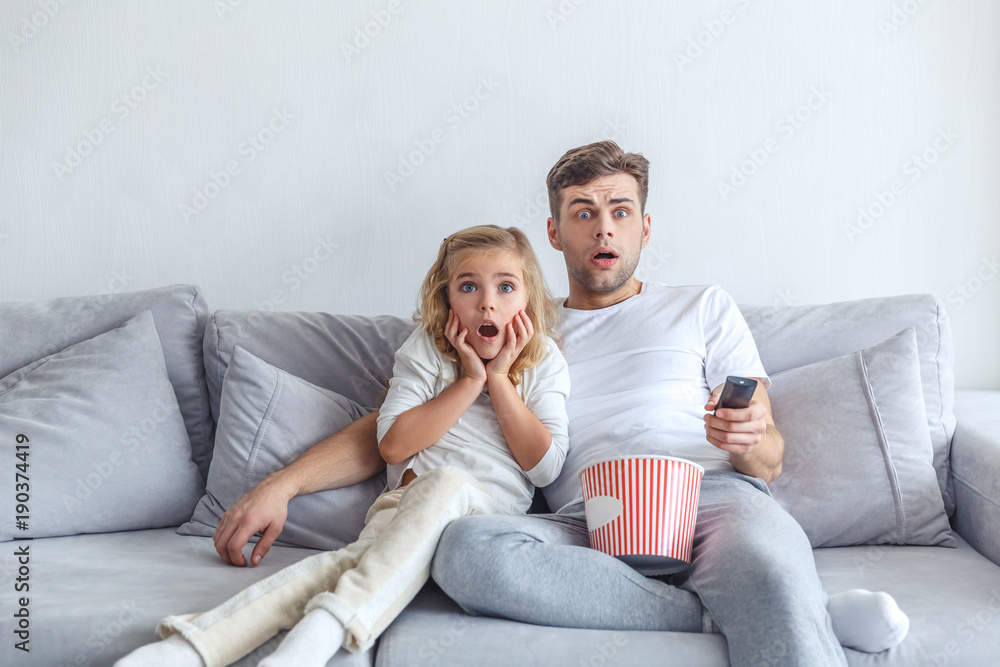 frightened father and daughter watching scarry movie at home frightened father and daughter watching scarry movie at home