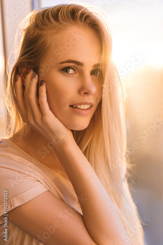 portrait of attractive young woman with sunset flare on background