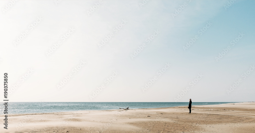 Woman walking on sandy coast.
