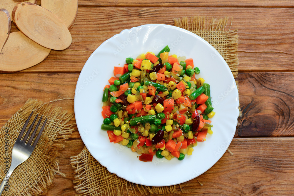 Vegan winter vegetable stew on a serving plate and wooden table. Home stewed carrots, green beans, red beans, peas, corn, pepper and onions. Healthy vegan stew recipe. Top view Vegan winter vegetable stew on a serving plate and wooden table. Home stewed carrots, green beans, red beans, peas, corn, pepper and onions. Healthy vegan stew recipe. Top view