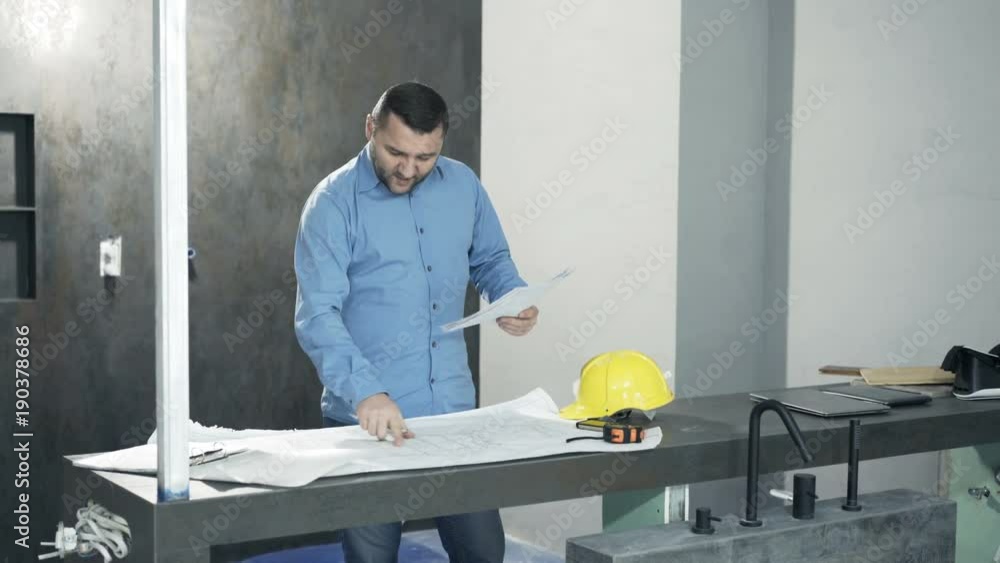 Young man with documents and blueprints talking to camera at new home
Young man with documents and blueprints talking to camera at new home