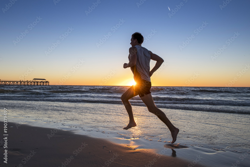 silhouette young dynamic athlete runner man with fit strong body training on Summer sunset beach running barefoot in sport healthy and fitness concept