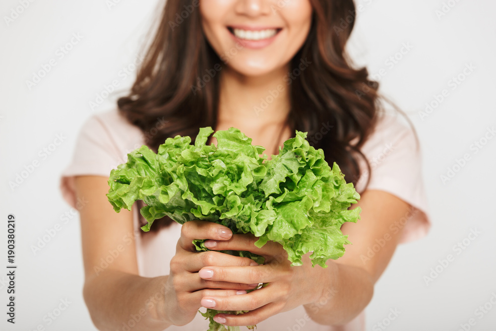 Cropped image of a smiling woman showing lettuce Cropped image of a smiling woman showing lettuce