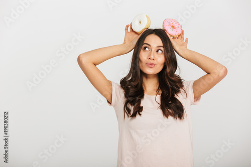 Portrait of a pretty young asian woman holding two donuts