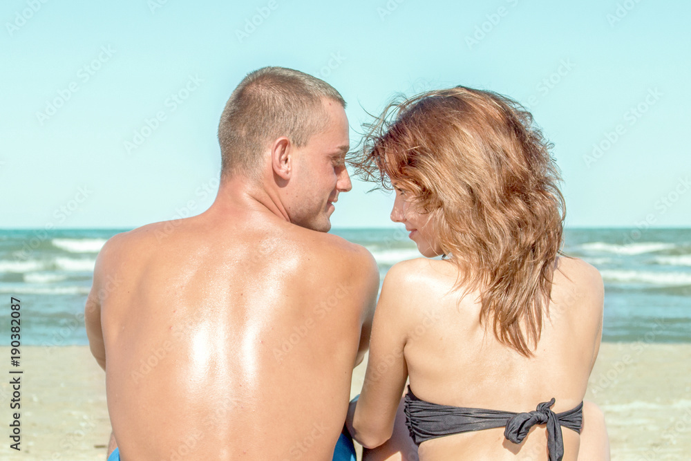 couple in love sitting on beach looking at each others couple in love sitting on beach looking at each others